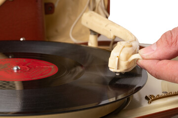 Man's hand lowers the foot of the pickup on a vinyl record in an old record player close up