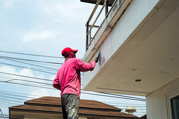 Fototapeta premium Rear view of worker removing the old color out of the surface of the cement wall