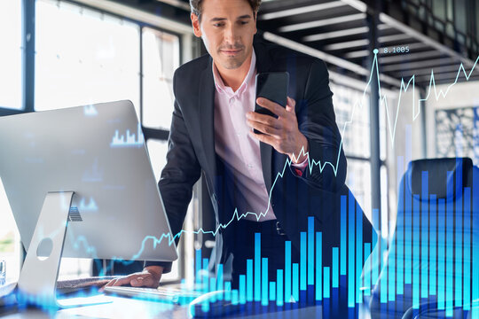 Businessman in suit using smart phone to optimize trading strategy at corporate finance fund. Forex chart hologram over modern panoramic office background