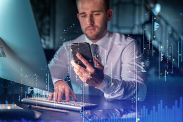 Businessman in casual wear using smart phone to optimize trading strategy at corporate finance fund. Forex chart hologram over modern office background at night time