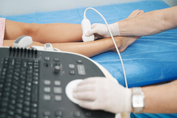 Medical specialist performing doppler ultrasound of the lower limb vessels - obrazy, fototapety, plakaty
