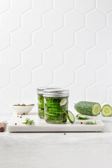 Pickled cucumbers. Slices of Marinated cucumbers in glass jars. Homemade fermented cucumbers. Tile white background