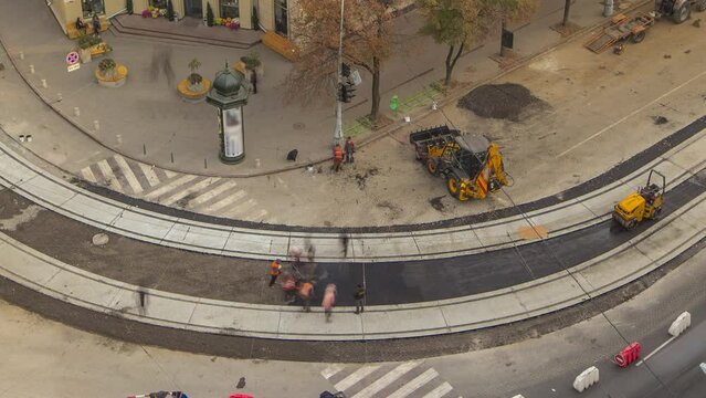 Construction site of avenue with asphalt paver, roller and truck aerial timelapse.