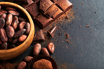 Chocolate bean cocoa. Composition of cocoa powder, bean cocoa bars and pieces of different milk and dark chocolate on black background. Baking Chocolate Texture. Top view with copy space. Mock up.