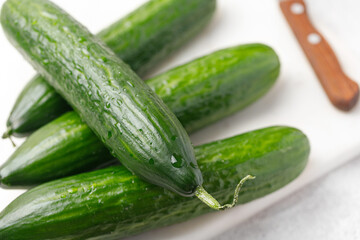 Four Cucumber with water drop on marble board with knife. Food preparing