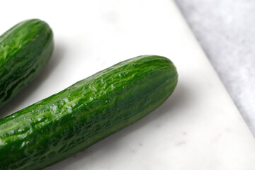 Two Cucumber on marble board with knife.