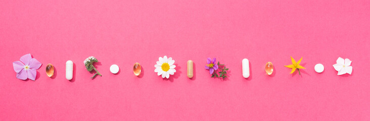Vitamin capsules and dietary supplements isolated on pink background. Panoramic format.