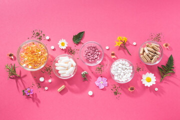 Flat lay composition of various dietary supplements on pink background. Vitamin complexes concept.
