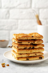 Fototapeta na wymiar Layered dessert with raisins in a white plate on a light gray culinary background. Delicious homemade sweet puff pastry closeup 