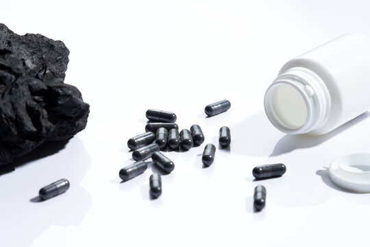 Vegetable carbon capsules on white background. Dietary supplements concept.