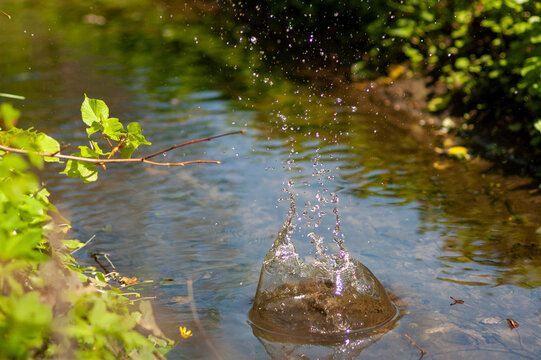Stein fliegt ins Wasser mit spritzendem Wasser