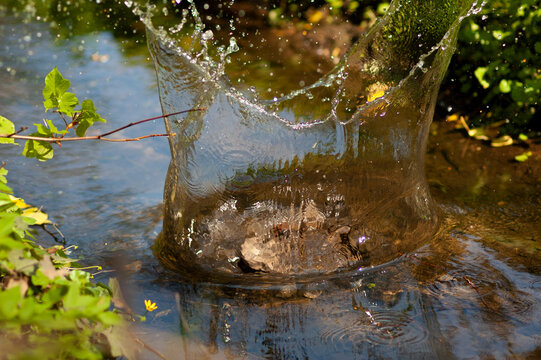 Stein fliegt ins Wasser mit spritzendem Wasser