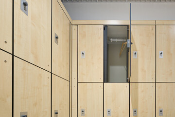 Gym locker room, beige doors with locks. Open door with rack and hanger. Organizing storage concept. Selective focus