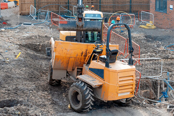 Excavator loading dumper during groundworks on new residential housing construction site