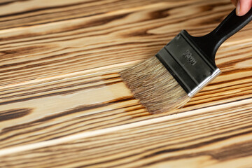 Wood processing - a stain is applied on the wooden base with a brush, while preserving the texture of the wood