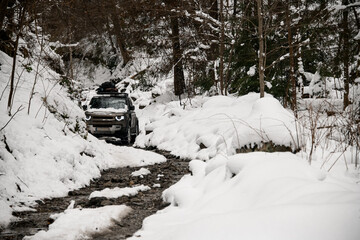 beautiful view of a rocky road in a snow-covered winter forest and off-road vehicle