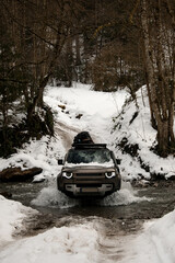 beautiful view of the off-road car driving through the river in the winter snowy forest