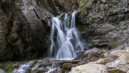 Fototapeta na wymiar Mountain waterfall among the rocks