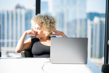 Young Light Skinned African-American Woman with Blonde Afro In deep thought in Front of Her Laptop