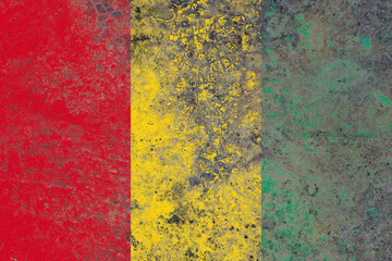 Guinea flag on a damaged old concrete wall surface