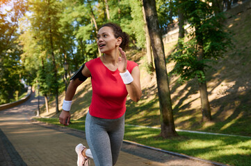 Stunning attractive middle aged fit woman, sportswoman, athlete, runner, jogger running on the city park. Fitness, cardio workout concept