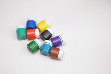 Bright jars with gouache paints of different colors on a light background. Drawing, hobby,...