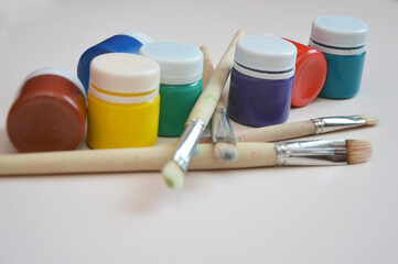 A set of jars of multicolored gouache and artistic bristle brushes. Free space for text. creativity, hobby, art, education.