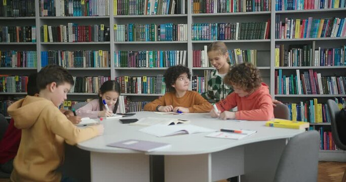 Multinational children sit at round table in school library