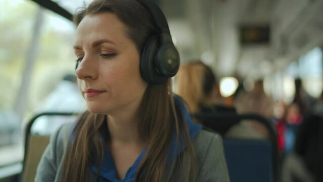 Woman listening to podcast or music while traveling in public transport. City, urban, transportation.