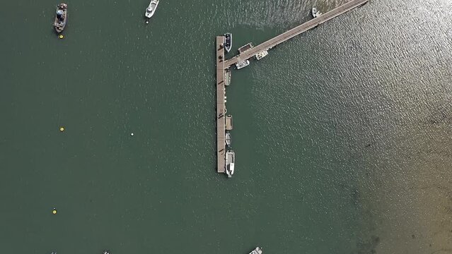 Aerial footage over sailing boats anchored by a jetty in the beautiful estuary in Chichester Harbour at Itchenor.