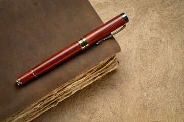 antique leather-bound journal or book with decked edge handmade paper pages and a stylish pen on a...