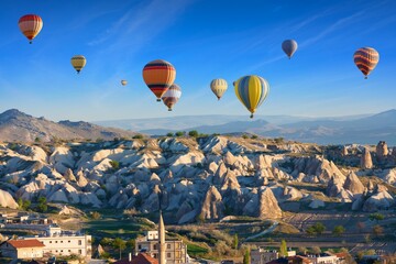 Colorful hot air balloons fly in blue sky over amazing rocky valley in Cappadocia, Turkey. - obrazy, fototapety, plakaty