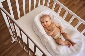 cute smiling baby lying in crib in cocoonababy top view