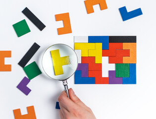 Hand with magnifying glass over suitable tetris puzzle piece. Better way of problem solution...