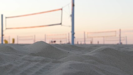 Players playing volleyball on beach court, volley ball game with ball and net, sunset palm trees...