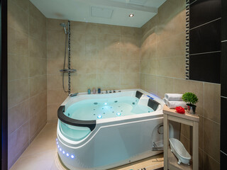 Illuminated massage bath with water. Interior of luxury bathroom.