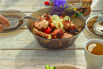 A man's hand with a fork fastens a pork shish kebab.