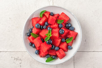 Watermelon salad with blueberries and mint in a plate on white table. Top view. Healthy summer...