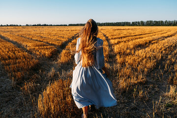 Woman in blue linen dress enjoying nature in sunset field. Stress and psychological resilience. Spend Time in Nature to Reduce Stress and Anxiety.