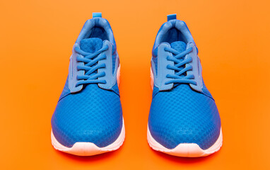 pair of comfortable sport shoes. sporty blue sneakers. shoes on orange background.