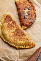 Homemade juicy golden deepfried turnovers chebureks on baking paper. Traditional Turkic-Mongolian dish. Street food