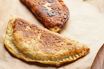 Homemade juicy golden deepfried turnovers chebureks on baking paper. Traditional Turkic-Mongolian dish. Street food