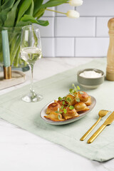 Deep fried traditional italian dish - ravioli, dumplings stuffed with minced meat, oregano branch, sour cream, a glass with champagne on green table cloth