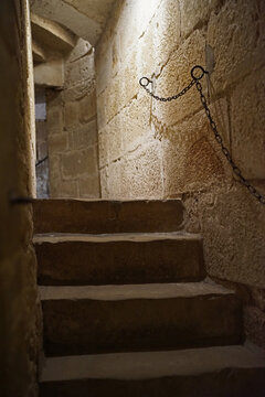 A stone staircase from the Middle Ages going to the prison cells. The bannister is a chain.
