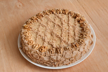  Homemade cake with walnuts on a white plate.