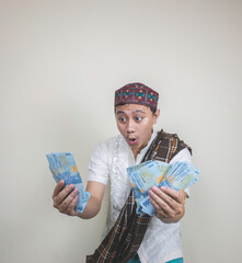 Happy asian man while holding a indonesian money. Isolated on white. Ramadan concept