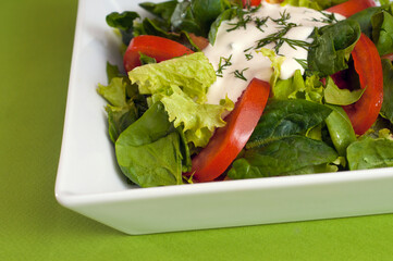 Green vegan summer lettuce with spinach, by tomatoes and sour cream. Healthy food concept.