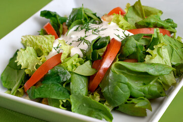 Green vegan summer lettuce with spinach, by tomatoes and sour cream. Healthy food concept.