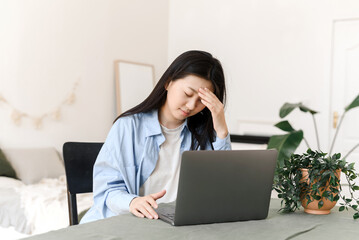 Stressed overworked business asian woman tired of working on laptop at home. Tired Korean woman suffering from headache, remote work concept