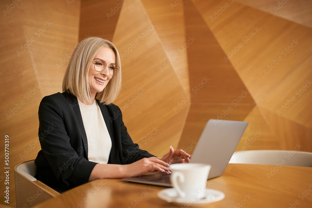 Wall mural mid adult businesswoman working on laptop at modern office